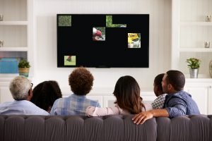 Men and Women sitting on couch watching a TV that is broken in places
